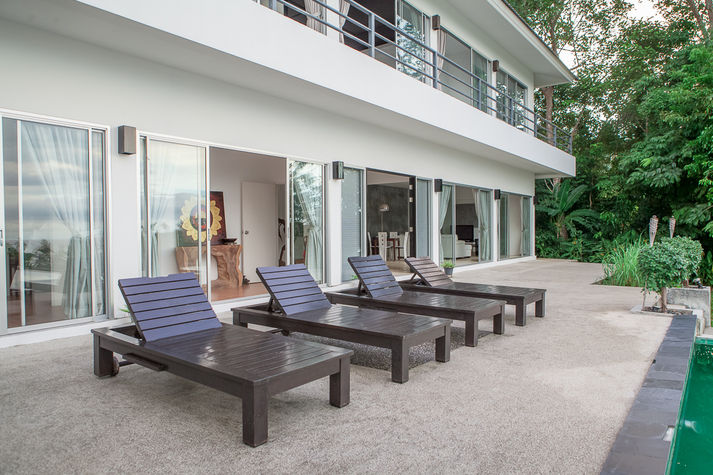 Pool deck with patio furniture and chaise-longues.