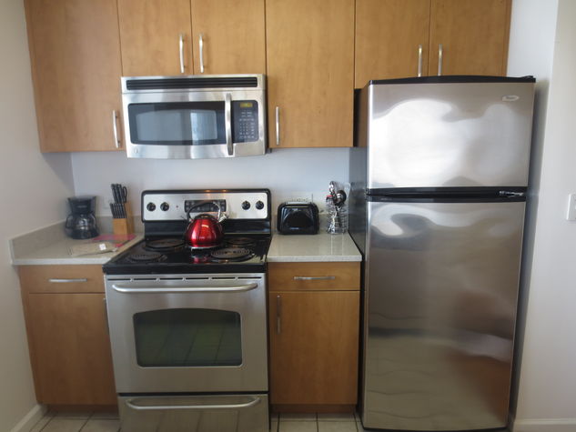 Fully equipped kitchen with stainless steel appliances, pots, pans and dishes