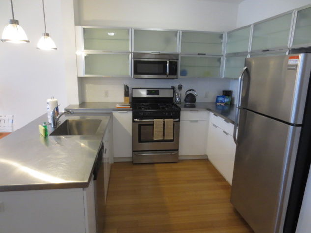 Fully equipped kitchen with stainless steel appliances, pots, pans and dishes
