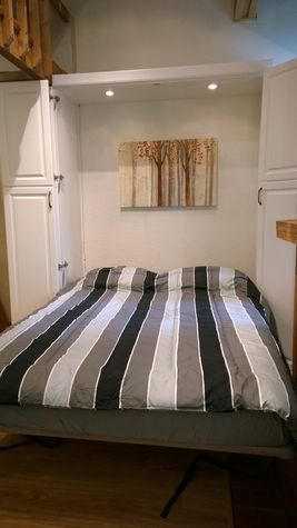 Customized queen-size murphy bed with reading light in main living room.