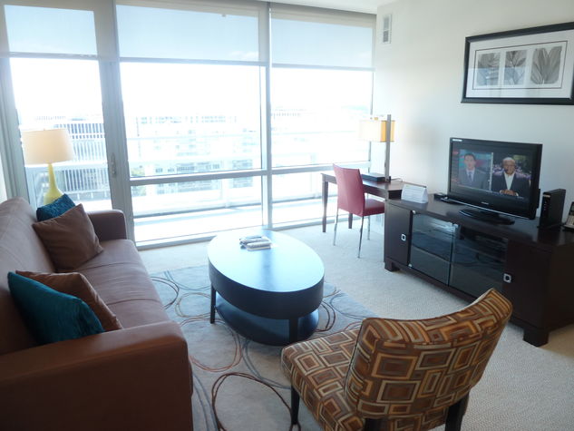 Living room with entertainment center, work desk and floor to ceiling windows