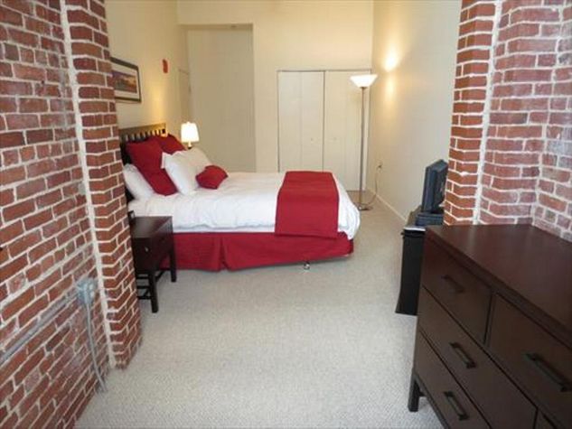 Private bedroom with queen size bed, large closet, exposed bricks and high ceiling