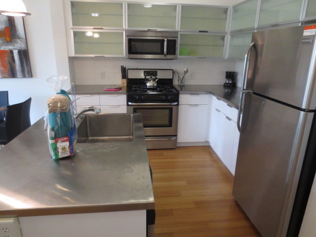 Fully equipped kitchen with stainless steel appliances, pots, pans and dishes