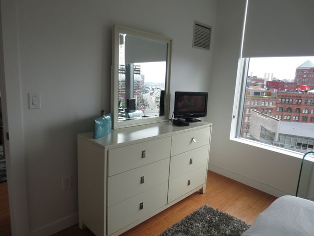 Bedroom with dresser, flat screen TV and large window providing lovely natural light