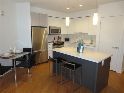 Modern kitchen with full size stainless steel appliances, pots, pans and dishes